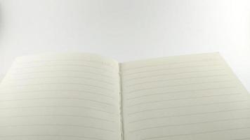 um caderno branco cremoso espalhado no centro e colocado sobre uma mesa branca. foto