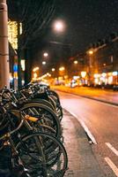 bicicletas estacionadas ao longo da estrada, noite foto