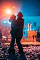 jovem casal adulto nos braços um do outro na rua coberta de neve. foto