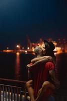 cara e garota se abraçando em um fundo do porto noturno foto