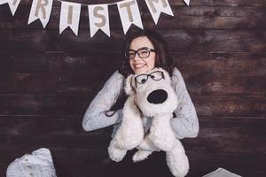 menina bonitinha abraçando um brinquedo fofo. fundo de natal foto