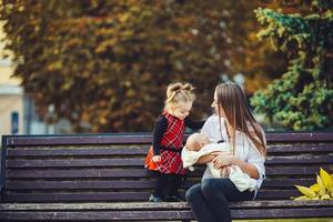 mãe e duas filhas descansam em um banco foto