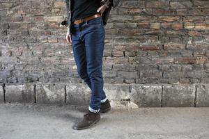 modelo masculino em jeans no fundo de uma parede de tijolos foto