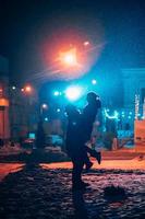 jovem casal adulto nos braços um do outro na rua coberta de neve. foto