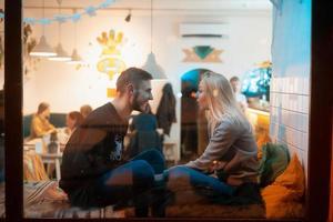 foto pela janela. jovem casal no café com interior elegante