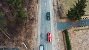 vários carros com caiaques no bagageiro dirigindo na estrada entre árvores foto