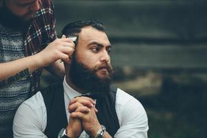 barbeiro depila um homem barbudo em atmosfera vintage