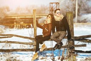 jovem casal sentado na cerca velha foto