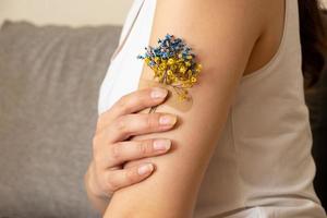flor azul e amarela sob o remendo na mão de uma mulher. o conceito de vacinação e tratamento na ucrânia foto
