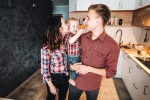 pai, mãe e filho pequeno cozinham uma torta foto