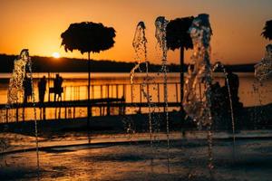 fluxo de uma fonte espirra água, pôr do sol foto