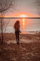 mulher aproveitando o tempo relaxante à beira do belo lago ao nascer do sol. foto