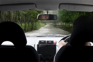 homem dirigindo carro na estrada de concreto. dois ao lado com a natureza da plantação de seringueiras. viajar para os recursos naturais das províncias. foto