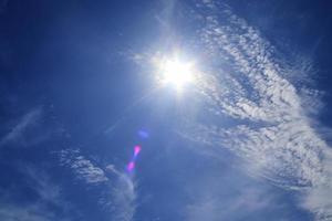 bela vista em raios de sol com alguns reflexos de lente e nuvens em um céu azul foto