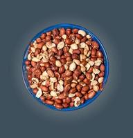 amendoins descascados para segundo plano. amendoim torrado com casca. isolado em uma placa azul em um gradiente cinza foto
