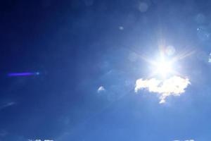 bela vista em raios de sol com alguns reflexos de lente e nuvens em um céu azul foto