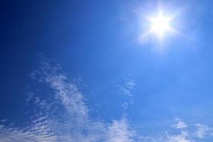 bela vista em raios de sol com alguns reflexos de lente e nuvens em um céu azul foto