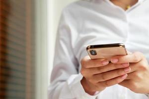 Feche a mão jovem em assistir a mensagem no celular inteligente durante as férias. usando telefones celulares para se comunicar no mundo online. com tela preta em branco ou vazia foto