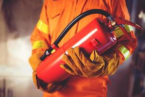mão de bombeiro segurando o extintor de incêndio. disponível em fundo de danos de conflagração de emergências. conceito de segurança. foto