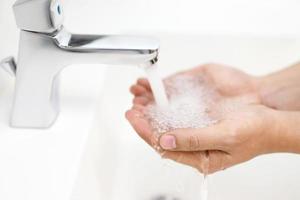 higiene. mãos de limpeza. lavar as mãos com sabão sob a torneira com água paga. foto