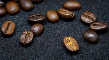 a forma como os grãos de café repousam sobre um fundo preto, grãos de café elegantes e deliciosos e o aroma do café da manhã. foto