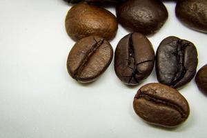 a forma como os grãos de café repousam sobre um fundo branco, grãos de café elegantes e deliciosos e o aroma do café da manhã. foto