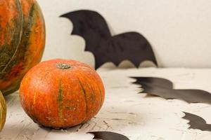 abóbora laranja e morcegos de papel na mesa branca, conceito de halloween foto