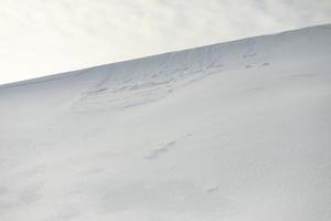 encosta nevada contra o céu. avalanche de neve no cume da montanha. clima frio. foto