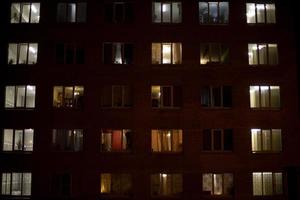 janelas na cidade noturna. luz das janelas em casa. apartamentos residenciais no escuro. foto