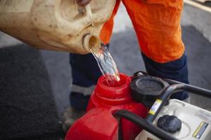 lata de gasolina. reabastecimento do motor diesel. trabalhador derrama combustível no tanque. foto