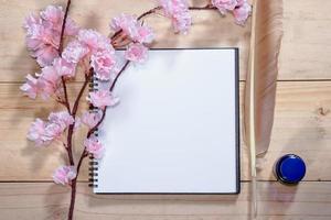 caderno aberto com flores de sakura rosa em fundo de madeira foto