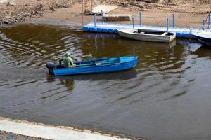 um pescador em um barco a motor azul flutua para o cais foto