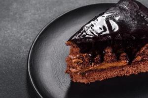 um pedaço de bolo delicioso fresco com nozes e chocolate em um prato preto
