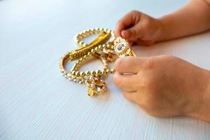 as mãos das crianças brincam com joias de ouro e bijuterias, sobre fundo branco. conceito de felicidade das mulheres foto