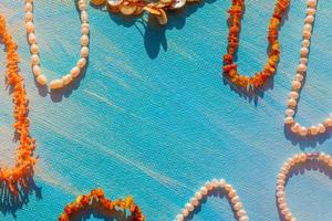 um conjunto de jóias naturais. espaço para o texto. pérola âmbar coral e jóias de osso em um fundo azul. vista do topo. foto