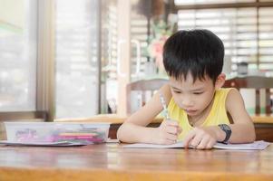 garotinho fazendo lição de casa para a escola na mesa em casa foto