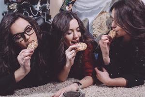 linda garota comendo biscoitos de natal e bebendo chá enquanto estava deitado em um tapete. apartamento vintage decorativo. foto