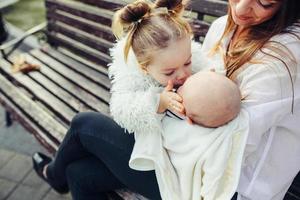 mãe e duas filhas descansam em um banco foto