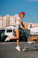 garota jovem e sexy posando com um carrinho em um estacionamento. foto