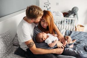 família feliz com bebê recém-nascido na cama foto