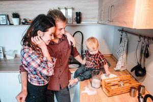 pai, mãe e filho pequeno cozinham uma torta foto