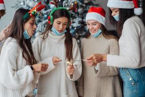 jovens multiétnicas comemorando a véspera de ano novo segurando estrelinhas foto