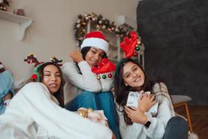 grupo multiétnico de amigos em chapéus de Papai Noel com presentes nas mãos. foto