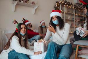 grupo multiétnico de amigos em chapéus de Papai Noel com presentes nas mãos. foto