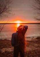 mulher aproveitando o tempo relaxante à beira do belo lago ao nascer do sol. foto