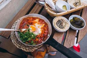 shakshuka, ovos fritos em molho de tomate em cima da mesa foto