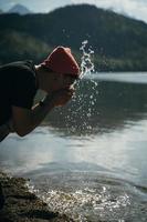 um homem lava as mãos na margem de um lago da floresta foto