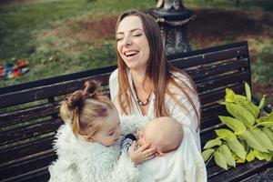 mãe e duas filhas descansam em um banco foto