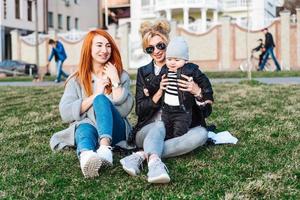 mãe e tia brincam com um menino no parque foto