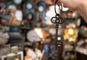 mão de uma mulher segurando uma chave antiga no fundo desfocado foto